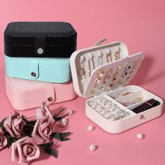 an open jewelry box sitting on top of a pink table next to flowers and pearls