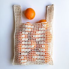 an orange sitting on top of a crocheted bag