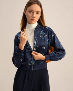 a model wearing a navy bomber jacket with a floral print Blue Printed Outerwear For Spring, Casual Paisley Print Spring Outerwear, Blue Printed Long Sleeve Outerwear, Casual Blue Printed Outerwear, Blue Floral Print Fall Outerwear, Blue Printed Outerwear For Winter, Winter Blue Printed Outerwear, Blue Printed Winter Outerwear, Bright Prints