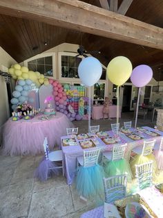 an outdoor party with balloons, cake and desserts on the tables in pastel colors