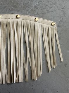 a white purse with tassels hanging from it's side on a wall