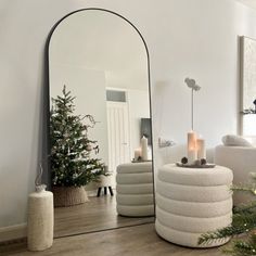 a mirror sitting on top of a wooden floor next to a christmas tree in a living room