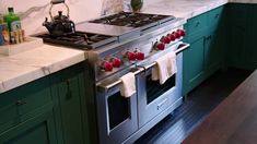 a stove top oven sitting inside of a kitchen next to a counter with tea kettles on it