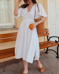 a woman in a white dress holding an orange