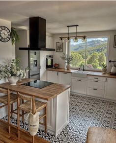 a kitchen with an island counter and wooden stools in front of a window overlooking the mountains