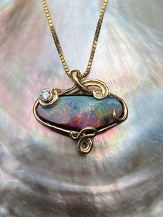 "18K gold  Rainbow Dawn Australian opal pendant is a one of a kind design lost wax cast in 18K gold.  Fluid wave caress a 12.84 carat Australian boulder opal radiating with a rainbow of iridescence. A .15 point diamond is bezel set in a the curl of a decending wave. The Dimensions of the pendant are 1\" across and 15/16\" high.  All Marty Magic Jewelry is packaged in a beautiful box, embossed with the gold foil Marty Magic dragon logo. Perfect for any occasion. Designed in Santa Cruz, California Unique Ear Cuffs, Boulder Opal Jewelry, Dragon Ear Cuffs, Magic Jewelry, Dragon Logo, Magic Dragon, Australian Opal Pendant, Modern Jewellery Design, Necklace Opal