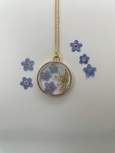 the necklace has blue flowers in it and is attached to a gold plated chain