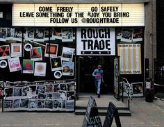 there is a sign that says rough trade on the side of this building with pictures all over it