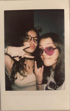 two young women making the peace sign with their hands while posing for a photo together