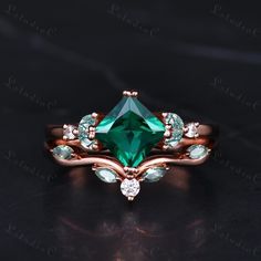 an emerald colored ring with white and green stones on the sides, set in rose gold