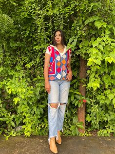 a woman is standing in front of some trees and bushes with her hands on her hips