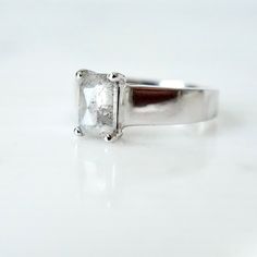 an engagement ring with a square cut diamond in the center, on a white surface