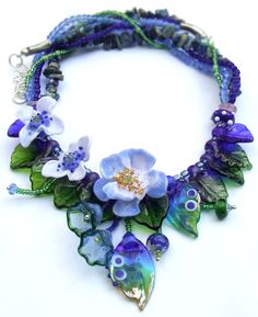 a necklace with blue flowers and green leaves