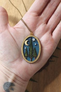 Welcome to our enchanting collection of wooden laser engraved diorama necklaces! Embrace your inner witchy vibes with these magical pieces featuring intricate designs of mushrooms, ferns, trees, and mini magic scenes. Each lightweight necklace is hand painted with care and comes on a beautiful brass chain. - Hand painted wood pieces add a unique touch to each necklace - Mini landscape scenes create a whimsical feel - Brass or gold chain adds a touch of elegance - Water resistant for everyday wea Handmade Magical Charm Necklaces For Gifts, Nature-inspired Round Pendant Jewelry For Crafting, Handmade Magical Pendant Necklace, Nature-inspired Pendant Jewelry For Crafting, Tree Of Life Round Pendant Necklace, Unique Tree Of Life Round Pendant Necklace, Mystical Handmade Necklaces For Gifts, Handmade Mystical Necklaces For Gifts, Magical Handmade Pendant Jewelry