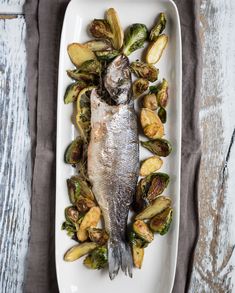 a fish is on a plate with potatoes and brussel sprouts in it