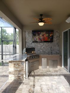 an outdoor kitchen with grill, sink and ceiling fan