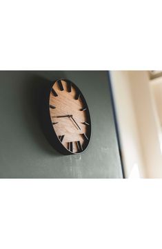 a wooden clock mounted to the side of a wall