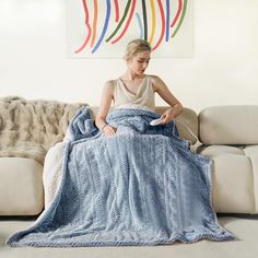 a woman sitting on a couch holding a blue blanket