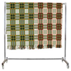 two different colored plaids hanging on a metal rack, one green and the other red