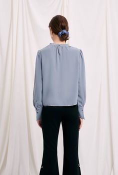 Everyone's favourite modern vintage Buvette Pearl blouse now updated in a pigeon-blue hue, featuring gently puffed sleeves, french cuffs and our signature pearl embellishment at the collar. Look office ready with our staple Emery pants and leather mules. Fabric: Soft, smooth and medium weight on the skin. Machine wash gentle (remove pearl) or hand wash. 100% Viscose. Fit Details: Relaxed fit. Fits true to size. Model measures 5'4", weighs 96 lbs and is wearing XS. Pearl Blouse, High Fashion Clothing, Look Office, High Fashion Outfits, Pearl Collection, Petite Jeans, Knitwear Tops, Leather Mules, Blue Hues