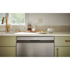 a dishwasher is sitting in the middle of a kitchen with green cabinets and white counter tops