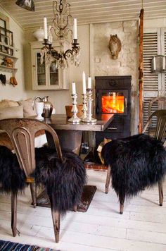 two chairs and a table in a room with an open fire place on the wall