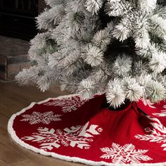 a white christmas tree with red and white snowflakes on it's base