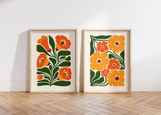 two framed art prints with orange and green flowers on the wall next to each other