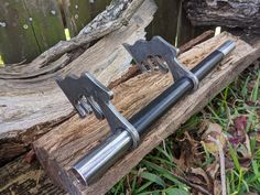 two metal objects sitting on top of a piece of wood next to a tree trunk