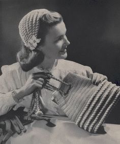 an old photo of a woman holding a knitted object in her right hand and smiling at the camera