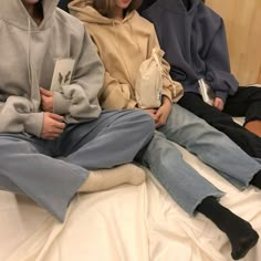 three people sitting on top of a bed