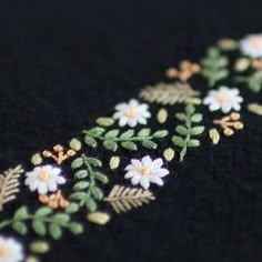 a close up view of some flowers on a black cloth with gold and white trim