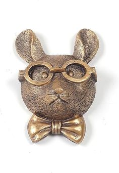 a brass colored rabbit with glasses and a bow tie on it's head is shown