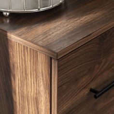 a close up of a wooden dresser with a metal bowl on top