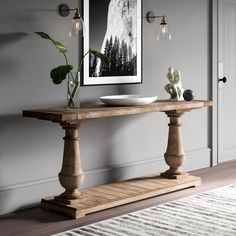 a wooden table with a bowl on it in front of a painting and a rug