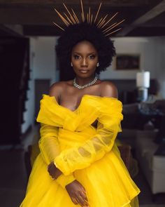 a woman in a yellow dress with long sleeves and an afro hairstyle is posing for the camera