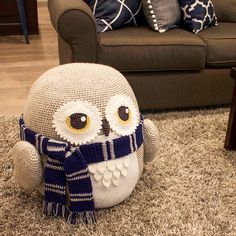 an owl sitting on the floor in front of a couch with pillows and throw pillows