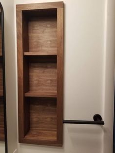 a wooden shelf sitting in the corner of a room next to a wall mounted mirror