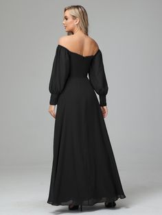 the back of a woman wearing a black dress with long sleeves and an open shoulder