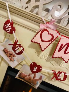 valentine's day decorations hanging from a fireplace mantel with photos and hearts on it