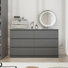 there is a large mirror on the dresser in this room with grey furniture and white walls