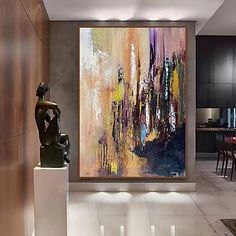 an abstract painting hangs on the wall next to a statue in a modern living room