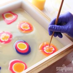 a person in blue gloves is painting flowers on the inside of a tray with liquid