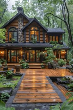 a large wooden house surrounded by trees and greenery in the evening time with lights on