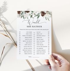 a person holding up a printable wedding game with flowers and greenery on it