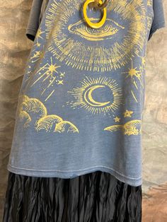 a t - shirt with an image of the sun and moon on it is hanging from a hanger