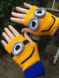 two hands wearing knitted yellow and blue mittens with eyes on them, one is holding the other hand