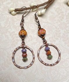 Boho earrings with rustic vibes.  These were created using small Czech Picasso rondelles in shades of green, terra cotta, and amethyst, a larger Czech rondelle in terra cotta, copper bead caps and spacers, and antique copper hammered connector hoops. For matching necklace, click on the link below: https://www.etsy.com/listing/1782426537/czech-glass-beaded-boho-necklace-with?click_key=82ee792fcb60d7941c87300d97fa47d6024c8247%3A1782426537&click_sum=53adc9de&ref=shop_home_active_2&pro=1 Total lengt Bohemian Czech Glass Jewelry For Everyday, Everyday Bohemian Czech Glass Jewelry, Bohemian Nickel-free Rust Earrings, Bohemian Rust-colored Nickel-free Earrings, Bohemian Rust Earrings With Ear Wire, Rust Bohemian Earrings For Pierced Ears, Everyday Bohemian Copper Jewelry, Rustic Handmade Hoop Earrings, Beaded Boho Necklace