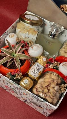 an open box filled with lots of different types of food and decorations on top of a red table