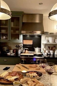 a kitchen counter topped with plates of food and glasses of wine next to an oven